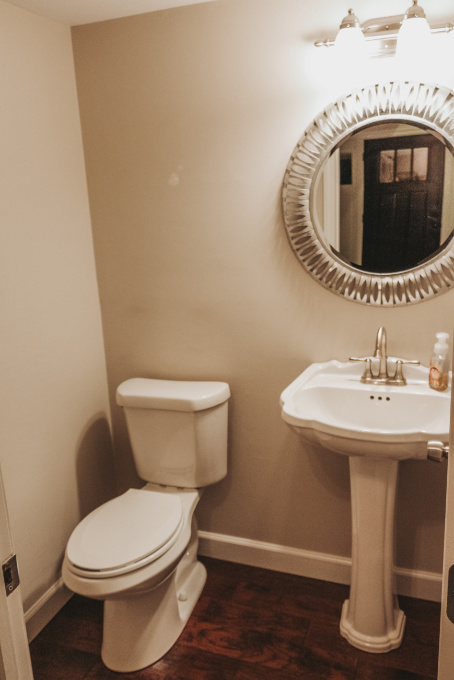 Half bathroom makeover shelving vintage industrial farmhouse decor plants modern glam metal mirror and blank wall over toilet before